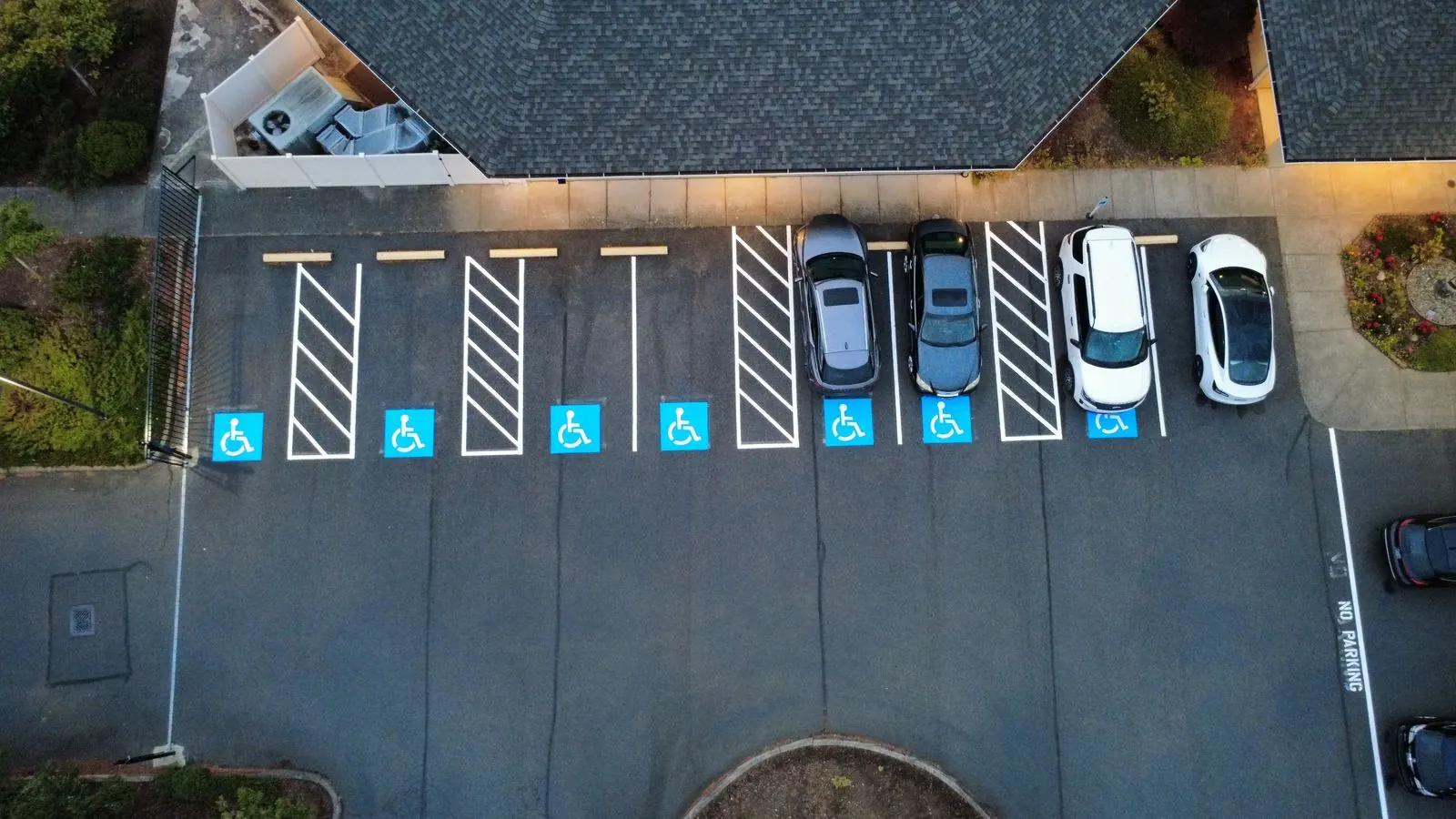 Row of ADA accessible parking stalls with blue symbols and hatched access aisles, daytime