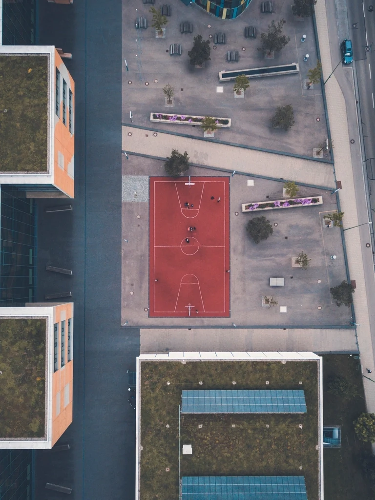 Top-down aerial view of a red outdoor basketball court with crisp white game lines