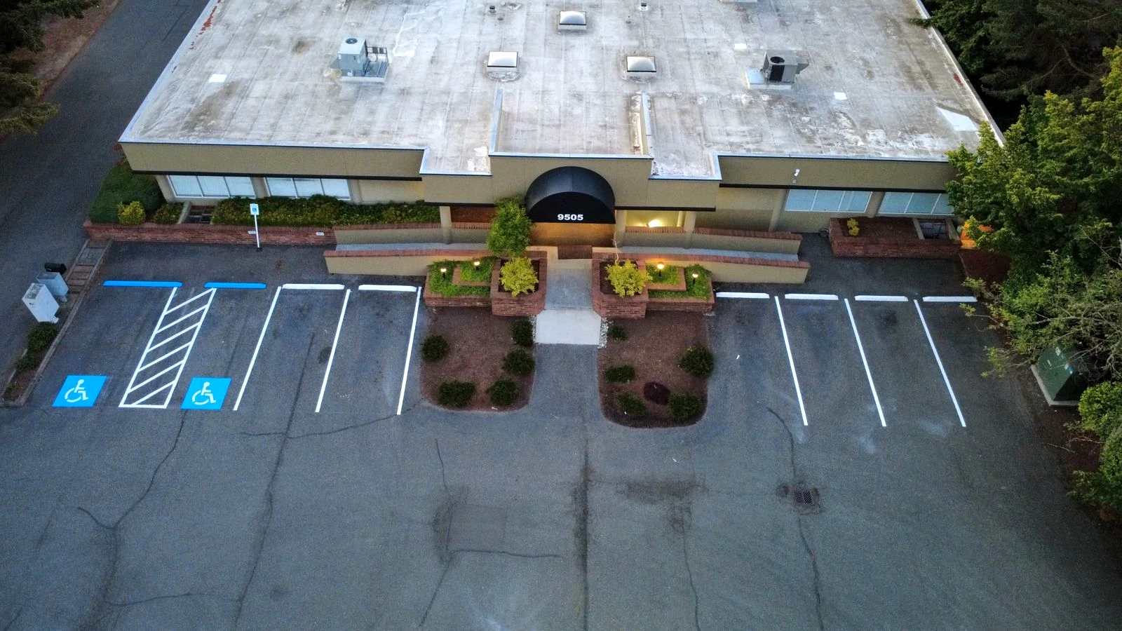 Aerial daytime view of ADA stalls and access aisle striping at a commercial building frontage