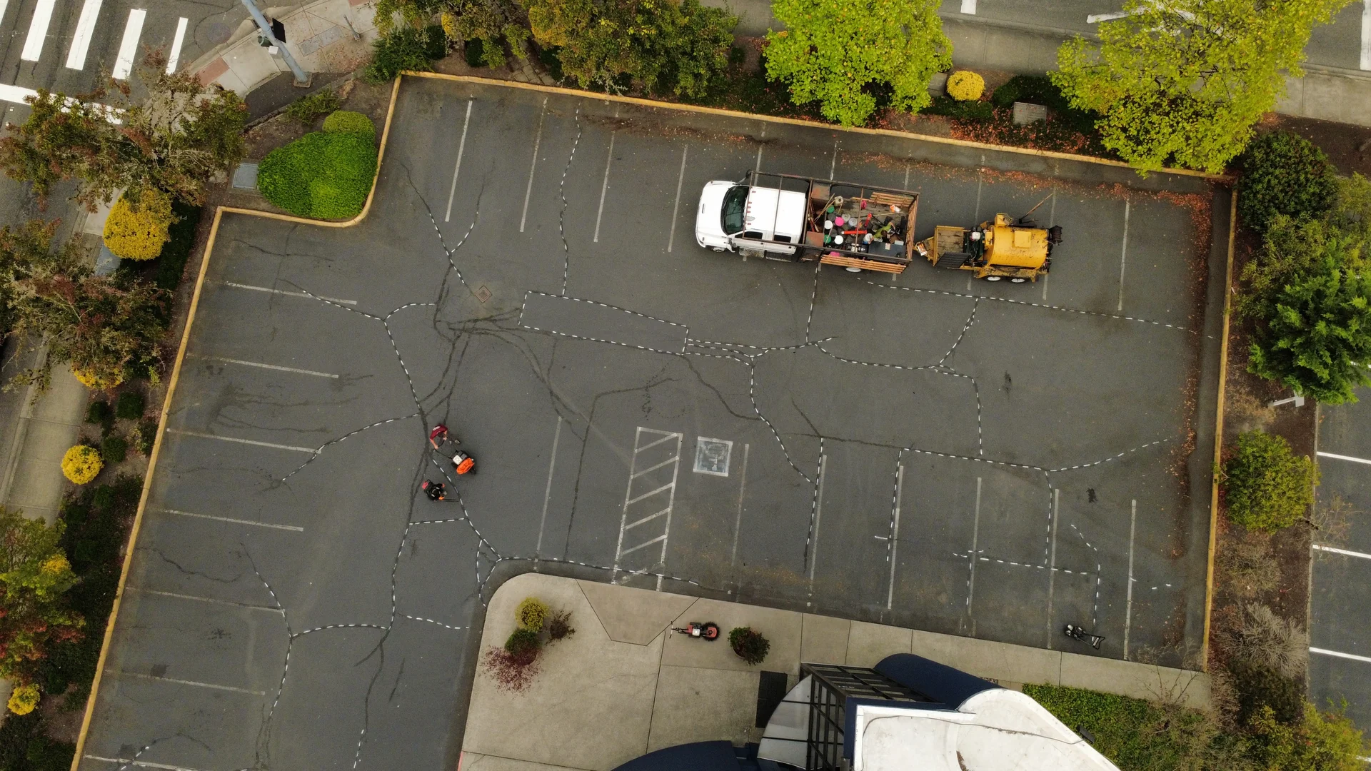 Prime Striping crew hot-sealing asphalt cracks before sealcoating a commercial lot