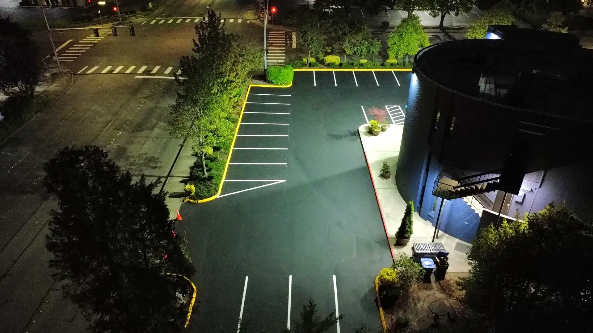Aerial night view of freshly striped parking lot with crisp white stalls and yellow curbs