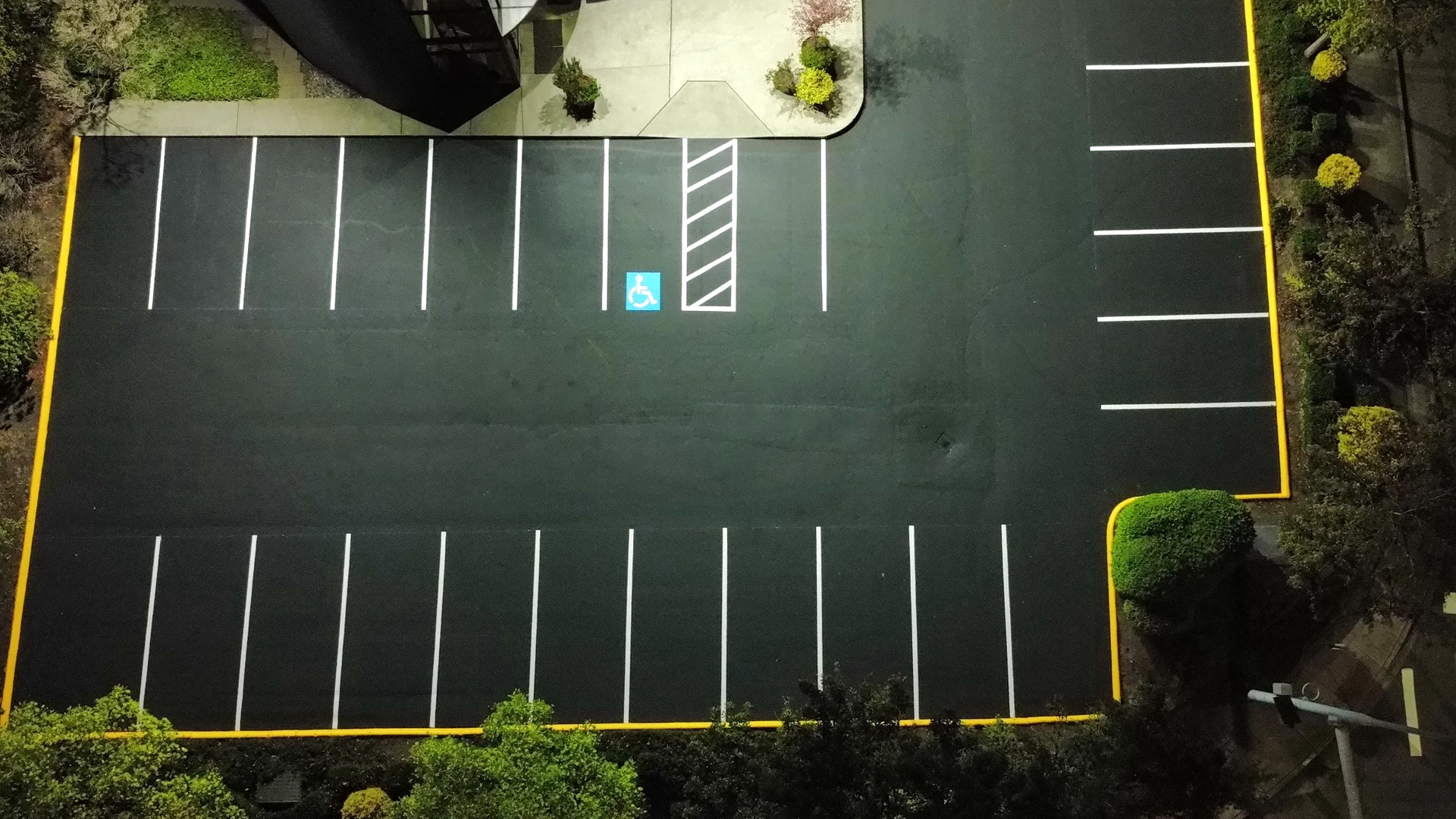 After — Tukwila parking lot freshly sealcoated jet-black with crisp new striping and yellow curbs